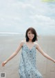 A woman in a blue dress standing on a beach.